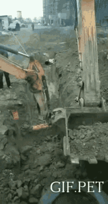 a large excavator is digging a hole in the ground with the words gif.pet below it