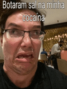 a man wearing glasses is making a funny face with the words botaram sal na minha cocaine written above him .