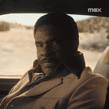 a man in a suit sits in the back seat of a car with the word max on the bottom right