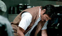 a man in a brown vest is kneeling down
