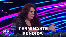 a woman with red hair is sitting at a table with a glass of water and says terminaste rendida .