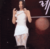 a woman in a white dress is standing in front of a sign that says " luyvwz "