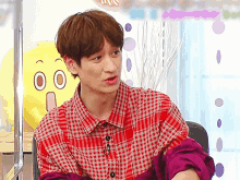 a man in a plaid shirt is sitting in front of a yellow cartoon face