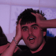 a man with a mustache is holding his head and making a surprised face