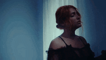 a woman in a black lace top is standing in front of a window