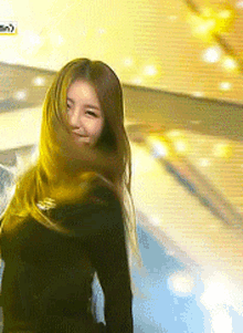 a woman with long hair is standing in front of a yellow background