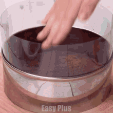 a person is putting a piece of cake in a clear plastic ring that says easy plus on the bottom