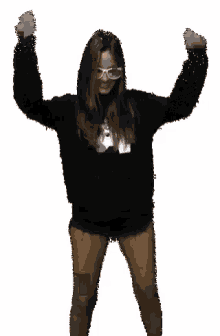 a woman wearing glasses and a black sweater is dancing with her hands in the air
