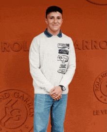 a man stands in front of a wall that says roland garros on it