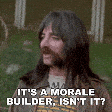 a man with long hair and a beard is saying it 's a morale builder isn 't it