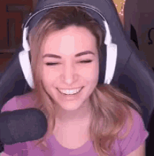 a woman wearing headphones and a purple shirt is sitting in a chair with a microphone .