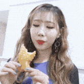 a woman with long hair is eating a piece of fried food