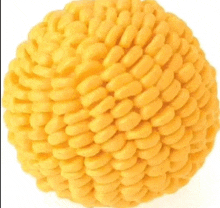 a close up of a yellow ball made out of corn on the cob on a white background .