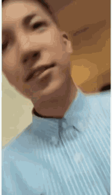 a close up of a man 's face wearing a blue striped shirt