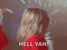 a little girl in a red jacket is holding a microphone and saying hell yah