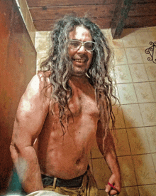 a shirtless man with long hair and glasses is smiling for the camera