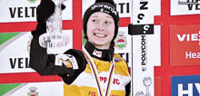 a woman wearing a goranj hat holds a trophy