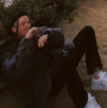 a person is laying on the ground with their legs crossed and a dog standing behind them .