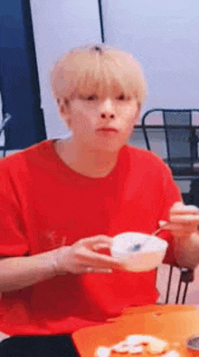 a man is sitting at a table eating food with chopsticks .