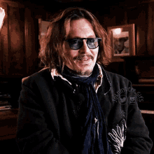 a man wearing sunglasses and a scarf has the name johnny dope written on his jacket