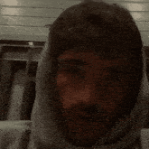 a man with a hood on his head looks to the side