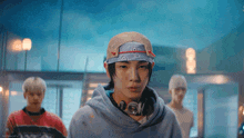 a man wearing a bandana and headphones is standing in a room with other men .