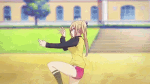 a girl in a yellow shirt is sitting on the ground with her arms outstretched .