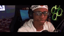 a man wearing glasses and a headband is sitting in front of a microphone and headphones .