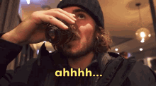 a man is drinking from a glass and the word ahhhh is on the bottom