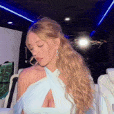 a woman with blonde hair is wearing a blue dress