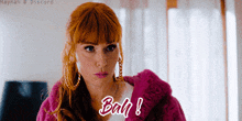 a woman with red hair is wearing a pink coat and earrings and says bah