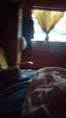 a blurry picture of a person sitting in front of a window with the sun shining through the curtains