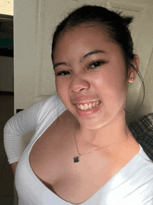 a woman wearing a white shirt and a necklace with a flower on it