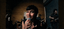 a woman is singing into a microphone while a man plays a guitar