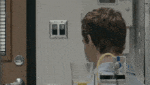 a man with a hose attached to his neck is looking at a light switch