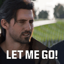 a man with a beard and a jacket says let me go