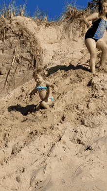 a little girl in a bikini is playing in the sand on a beach
