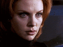 a woman with red hair and green eyes looks at the camera