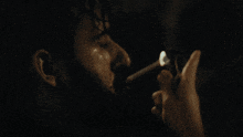 a man with a beard is smoking a cigarette in a dark room