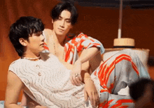 a couple of men are laying on a bed .