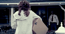 a woman carrying a cardboard box with the letter t on the side