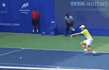a man is playing tennis on a court with a tata motors ad behind him