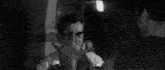 a black and white photo of a person 's face with a broken glass in the background .