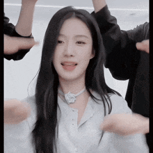 a woman with long black hair is wearing a white shirt and a flower necklace