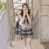 a girl wearing a plaid skirt is walking down stairs