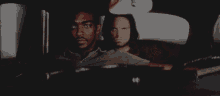 two men are sitting in the back seat of a car looking out the window .