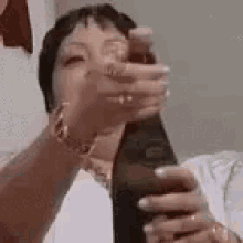 a woman is holding a bottle of wine in her hand and drinking it .