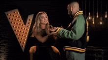 a man in a green jacket is talking to a woman in a black dress