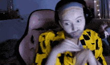 a woman wearing headphones and a yellow shirt is making a funny face while sitting in a chair .