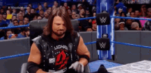 a wrestler is sitting in a chair in front of a crowd .